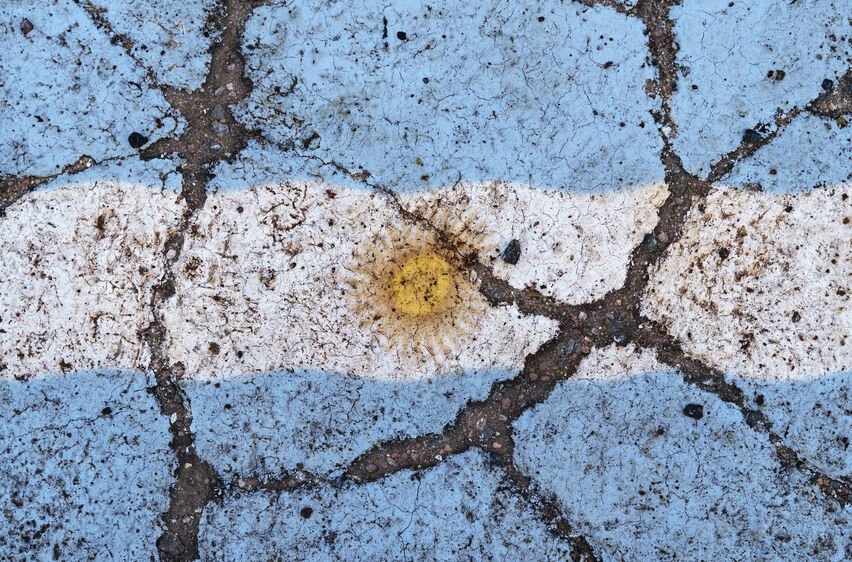 Argentina flag on cracked asphalt. The concept of crisis, default, pandemic, conflict, terrorism. Out of focus image