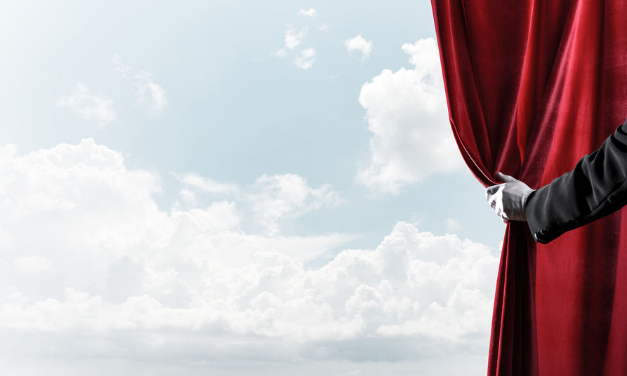 Cloudy landscape behind red curtain and hand holding it Cloudy landscape behind red curtain and hand holding it