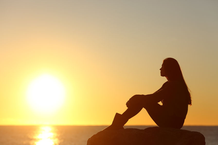 Woman silhouette watching sun in a sunset Woman silhouette watching sun in a sunset