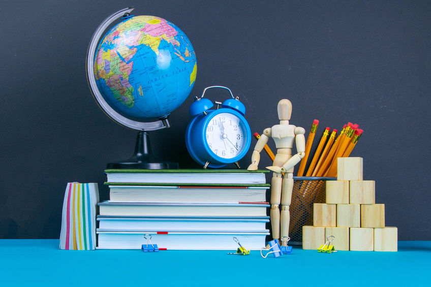 The globe and the clock stand on a stack of books, next to a glass of pencils and the pyramid is folded with wooden cubes and the figure of a wooden man