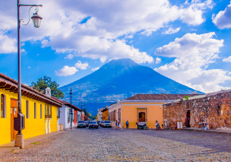 Ciudad de Guatemala, Guatemala, April, 25, 2018: View of antigua city, with some cars waiting over a toned pavement street, surrounding of old buildings, and the Agua volcano in the background