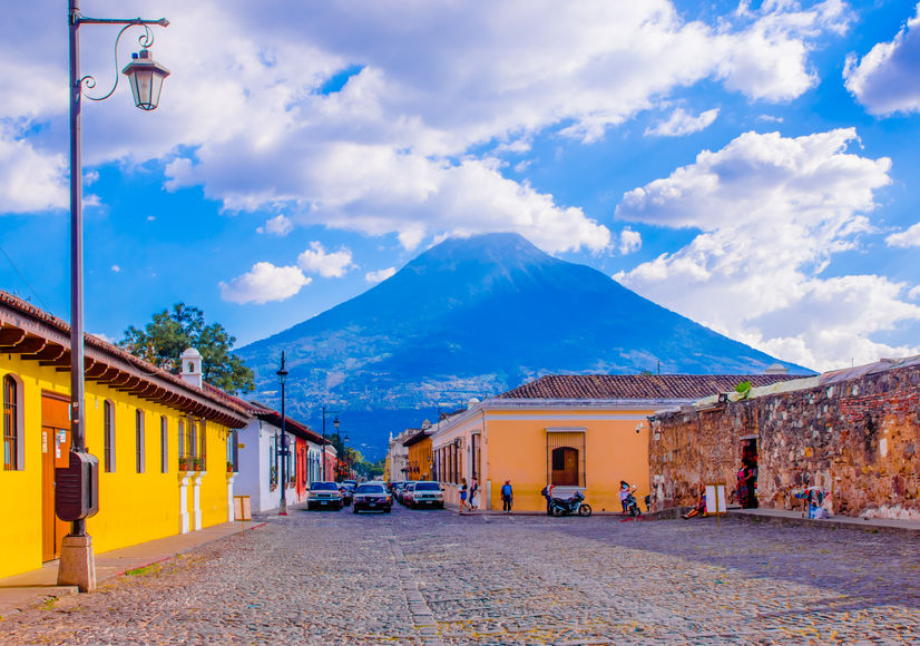 Ciudad de Guatemala, Guatemala, April, 25, 2018: View of antigua city, with some cars waiting over a toned pavement street, surrounding of old buildings, and the Agua volcano in the background