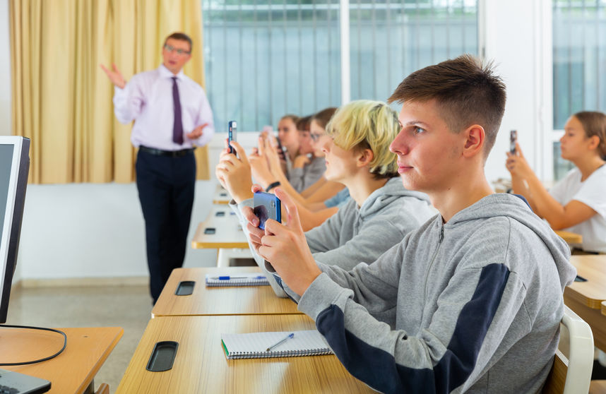 Schoolchildren with mobile phones in informatics lesson