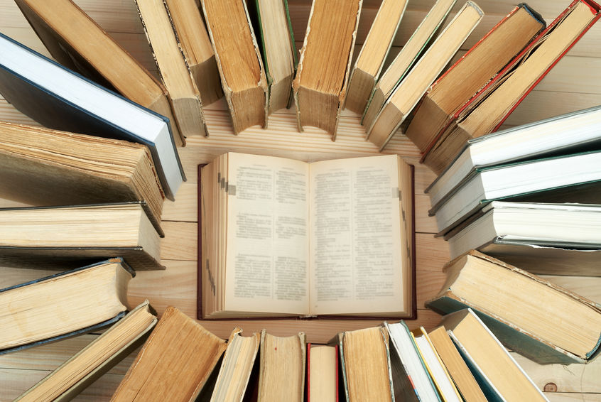 Open book, stack of hardback books on wooden table. Back to school. Copy space