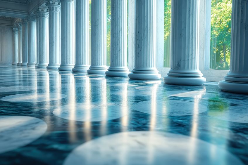 Majestic columns and polished floor reflect light in a serene, sunlit hall during daytime