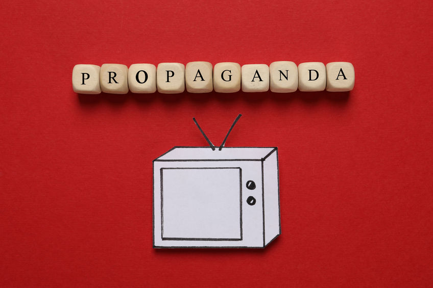 Word Propaganda made of wooden cubes and paper TV on red backgro