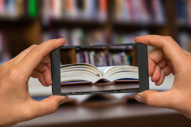 Taking photo of open book in library with mobile phone