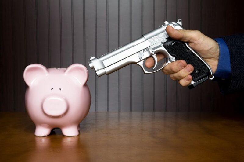 7792873 man pointing a gun at a piggy bank