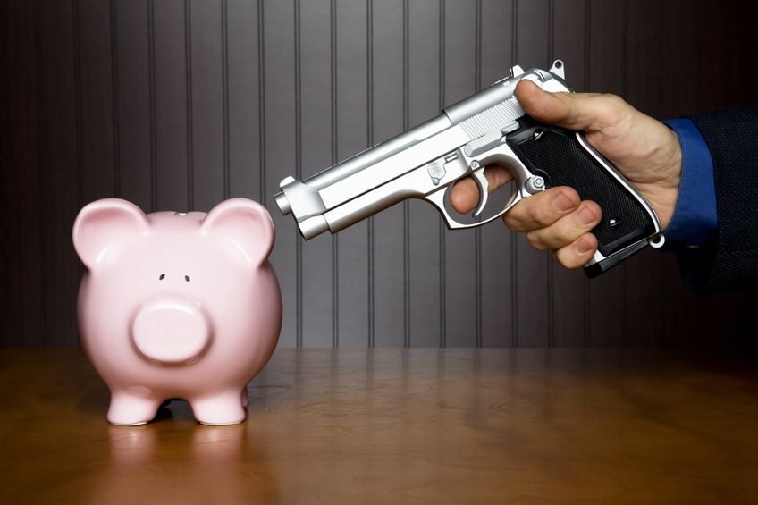 7792873 man pointing a gun at a piggy bank