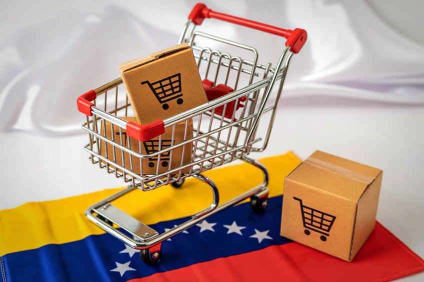 Miniature shopping cart with boxes on venezuelan flag symbolizing commerce